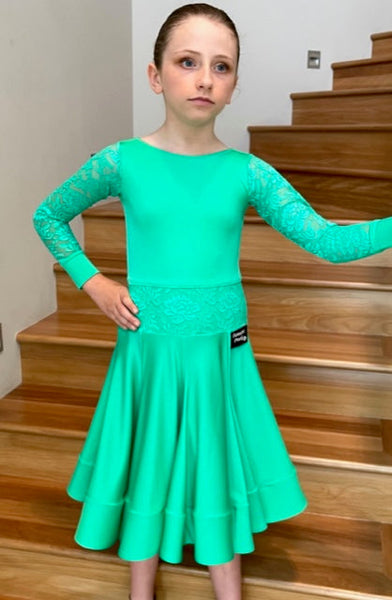 This elegant & eye catching girls Juvenile Dance Dress is ready to wear, made in Australia using quality fabrics by Chrisanne Clover.  Featuring a built-in leotard with lace sleeves with lycra cuffs, feature lace at the waistline, scoop neckline 